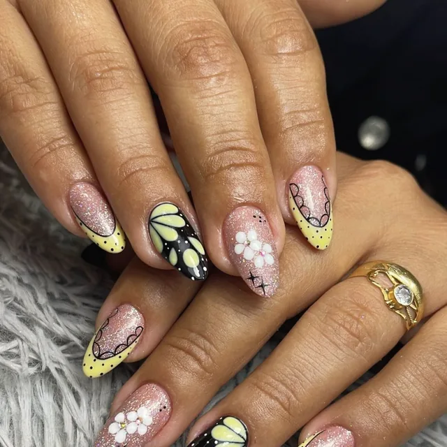 Uñas con mariposas amarillas y flores blancas sobre brillo rosa